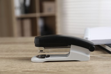 Photo of One stapler on wooden table indoors, closeup