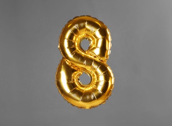 Golden number eight balloon on grey background