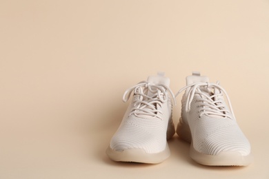 Photo of Pair of stylish sport shoes on beige background. Space for text