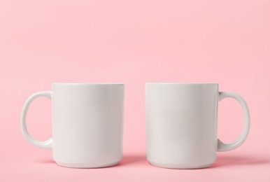 Photo of Two white ceramic mugs on pink background