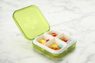 Photo of Plastic box with different pills on white marble table
