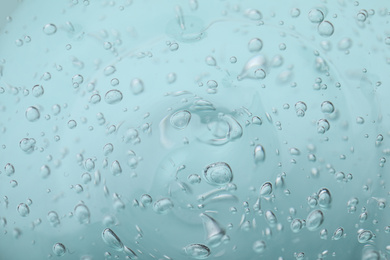 Photo of Pure transparent cosmetic gel on light blue background, closeup