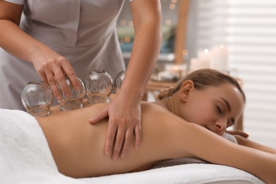 Photo of Therapist giving cupping treatment to patient in spa salon