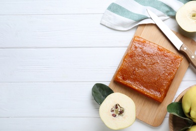 Delicious quince paste and fresh fruits on white wooden table, flat lay. Space for text