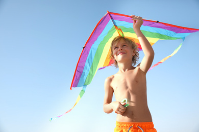 Photo of Cute little child playing with kite on sunny day. Beach holiday