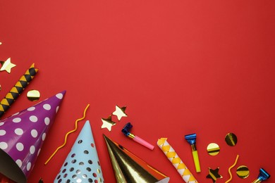 Flat lay composition with party hats and other festive items on red background. Space for text