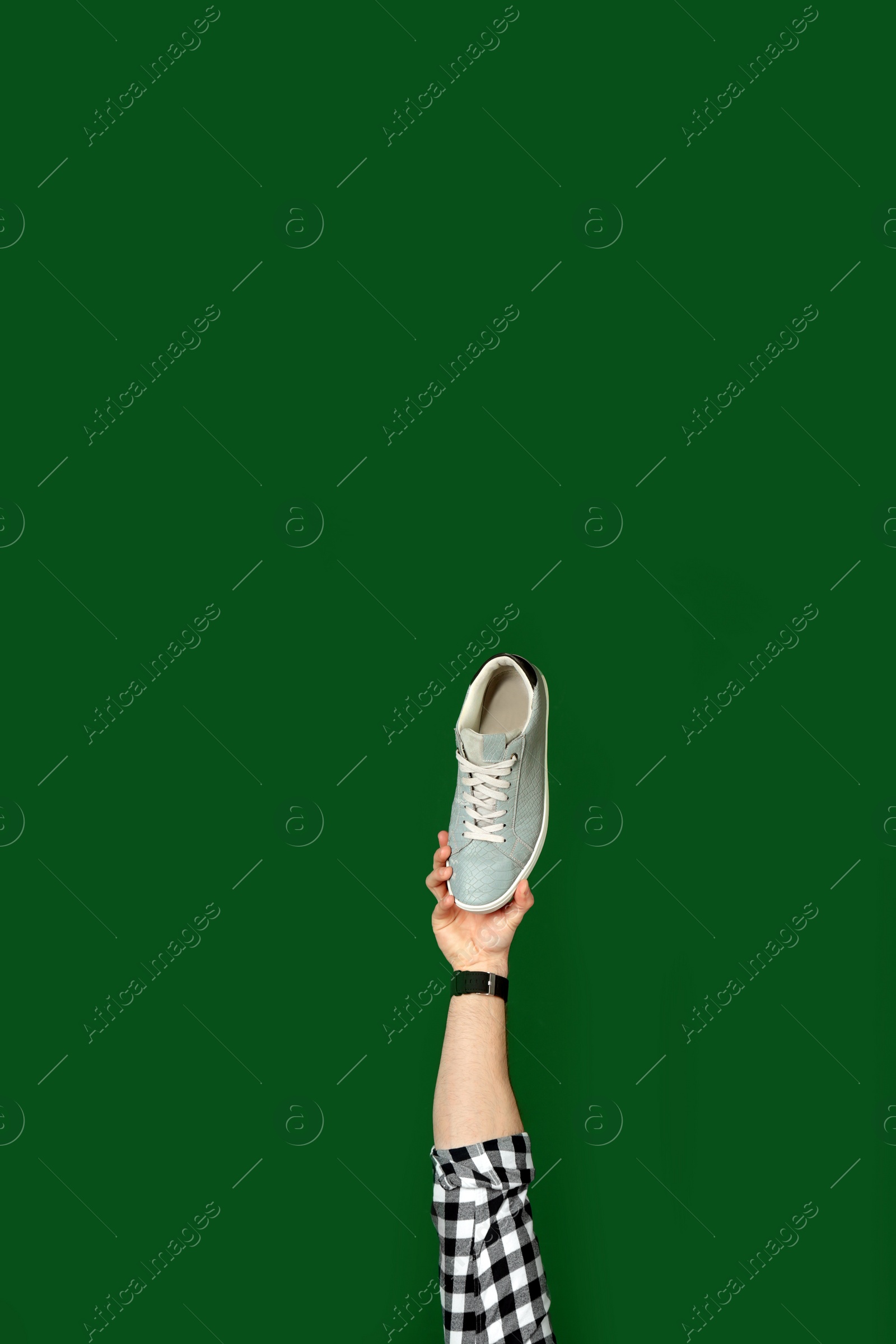 Photo of Man holding stylish shoe on green background, closeup