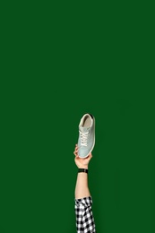 Photo of Man holding stylish shoe on green background, closeup