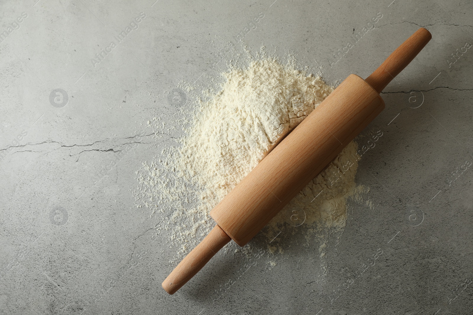 Photo of Flour and rolling pin on grey table, top view