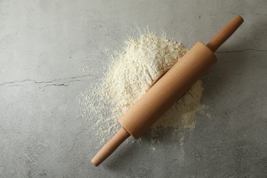 Photo of Flour and rolling pin on grey table, top view