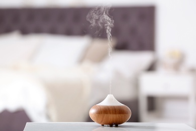 Photo of Aroma oil diffuser lamp on table against blurred background