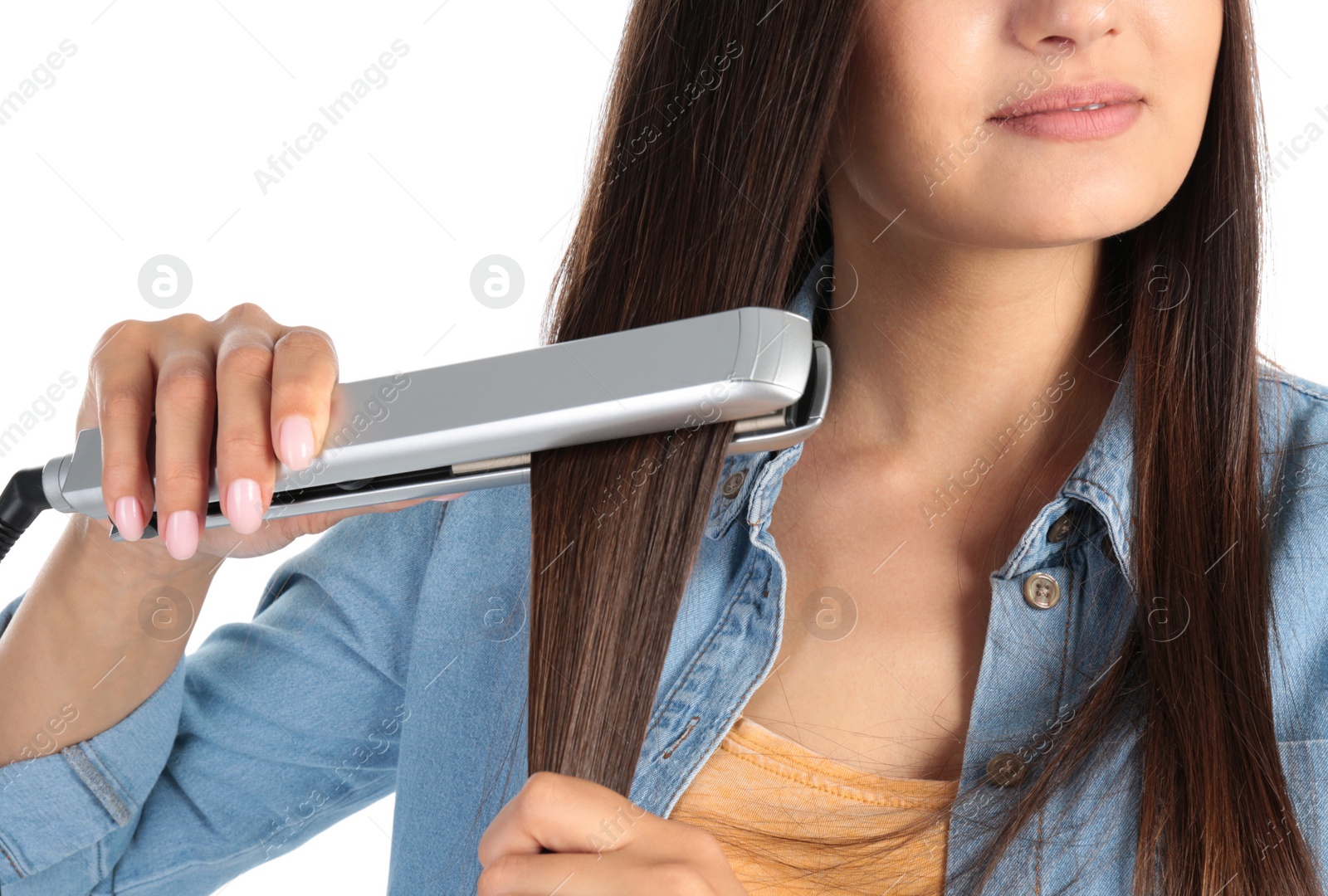 Photo of Young woman using hair iron on white background, closeup