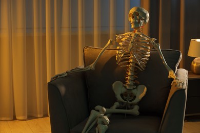 Waiting concept. Human skeleton sitting in armchair indoors, space for text