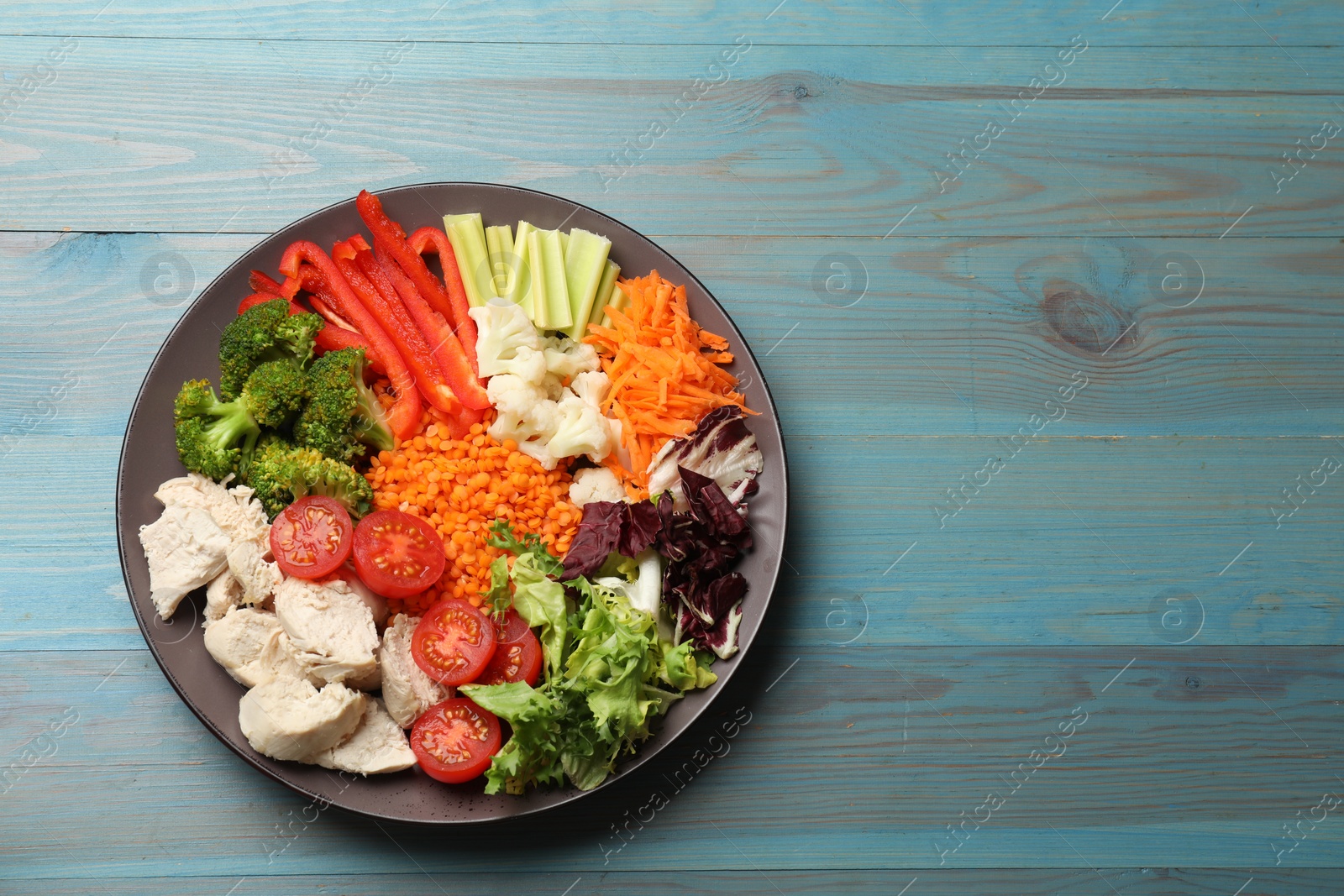 Photo of Balanced diet and healthy foods. Plate with different delicious products on blue wooden table, top view. Space for text