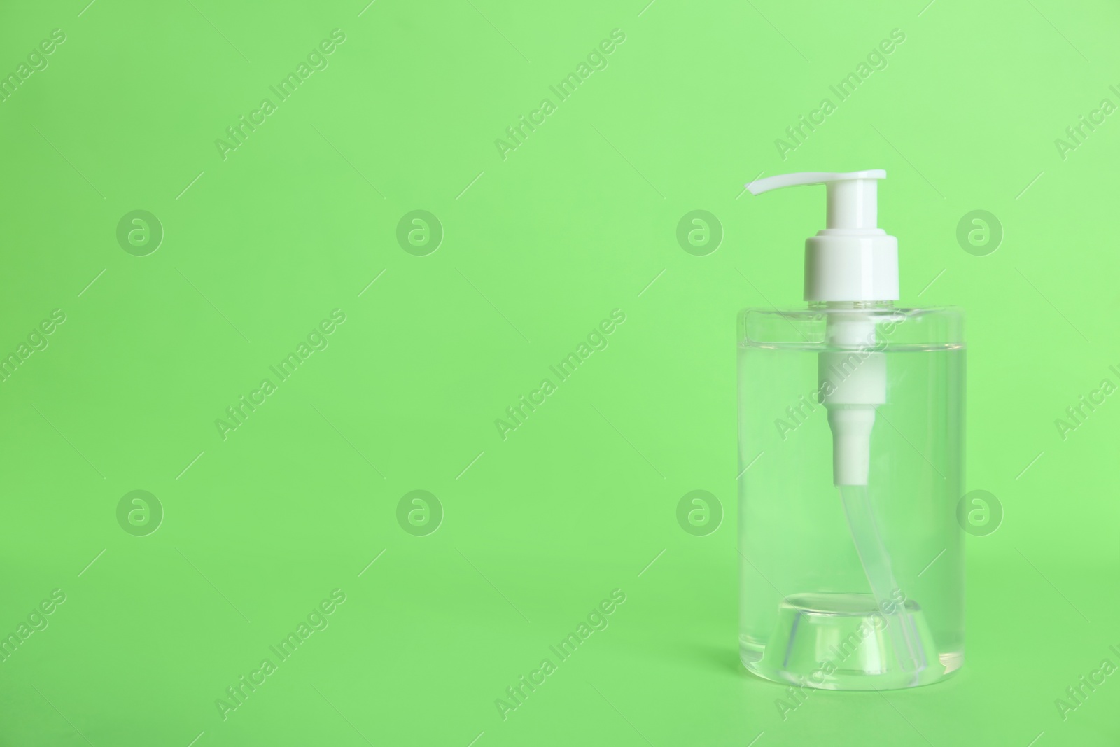 Photo of Dispenser bottle with antiseptic gel on green background. Space for text