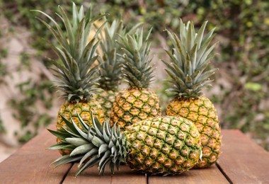 Delicious ripe pineapples on wooden table outdoors