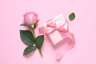 Photo of Gift box and beautiful rose flower on pink background, flat lay