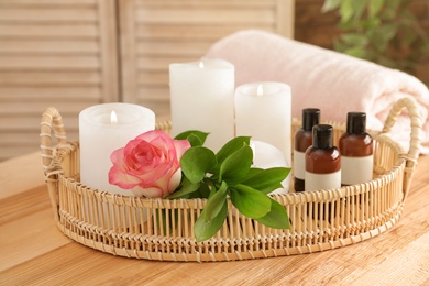 Photo of Tray with rose, essential oils and candles on table. Spa treatment