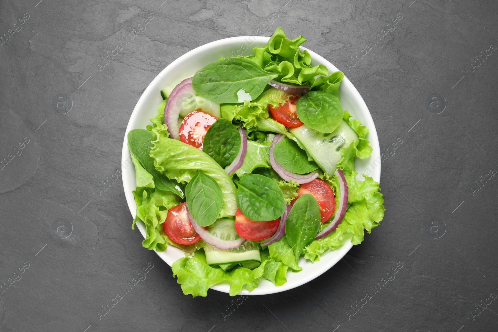 Photo of Delicious vegetable salad on grey table, top view