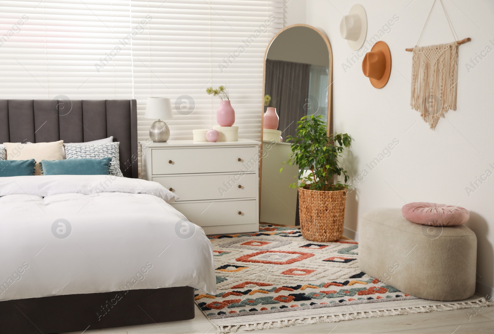 Photo of Comfortable bed with cushions, houseplant and different decor elements in room. Stylish interior