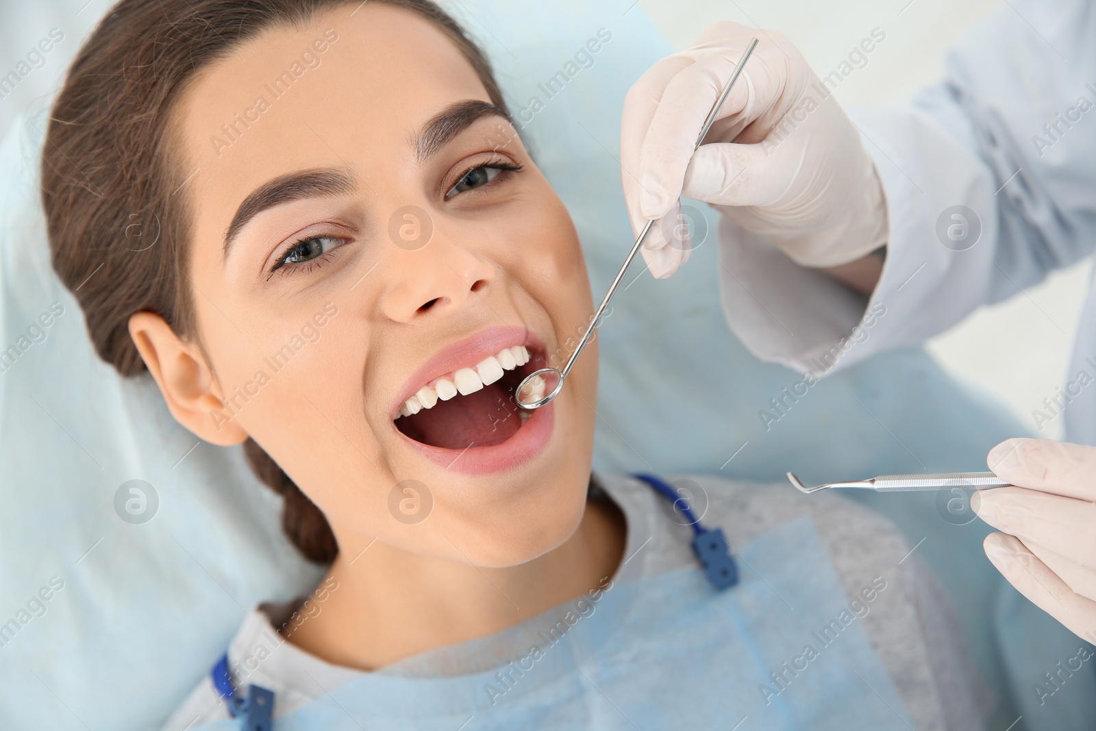 Photo of Dentist examining patient's teeth in modern clinic