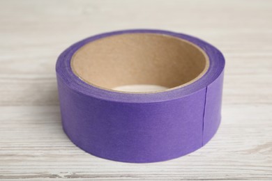 Photo of Roll of violet adhesive tape on wooden table, closeup