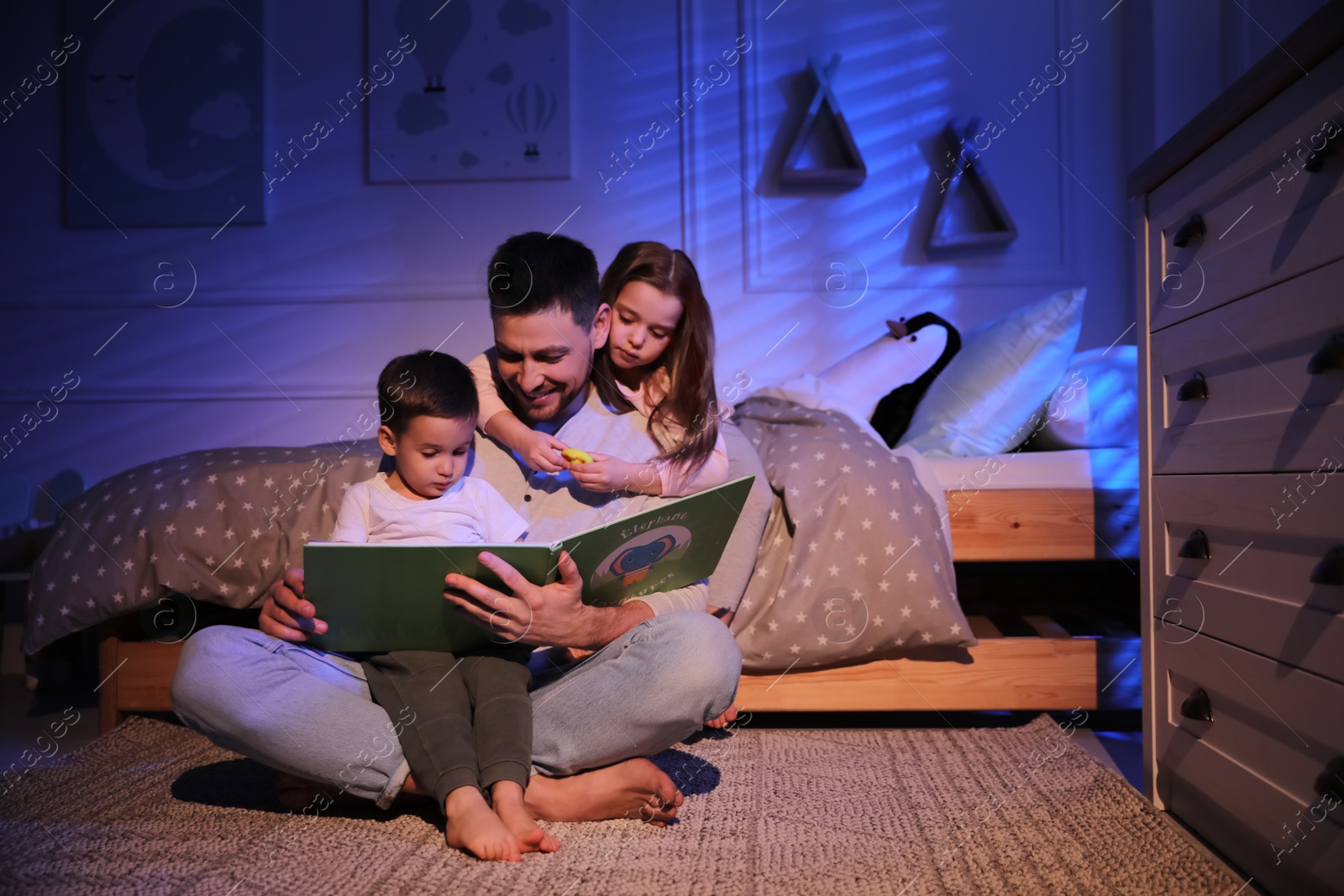 Photo of Father reading bedtime story to his children at home