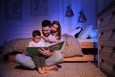 Father reading bedtime story to his children at home