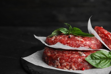 Photo of Raw meat cutlets for burger on black table, closeup. Space for text