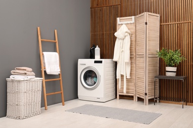 Photo of Washing machine with dirty towels in modern laundry room