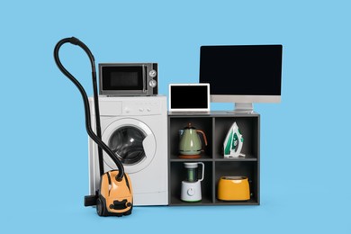 Photo of Set of different home appliances with vacuum cleaner on light blue background