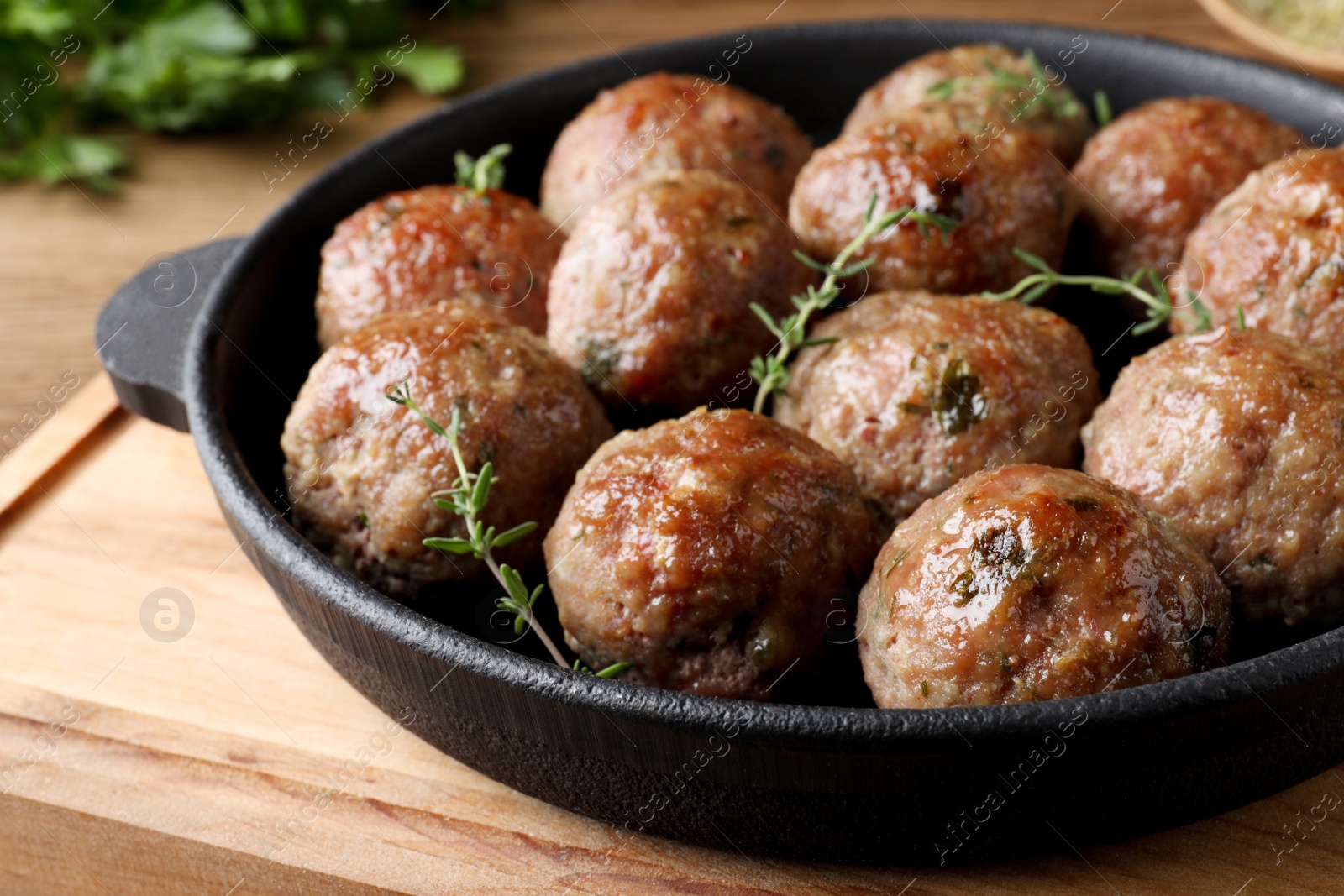 Photo of Tasty cooked meatballs served on wooden board, closeup