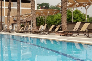 Photo of Sunbeds near swimming pool at luxury resort