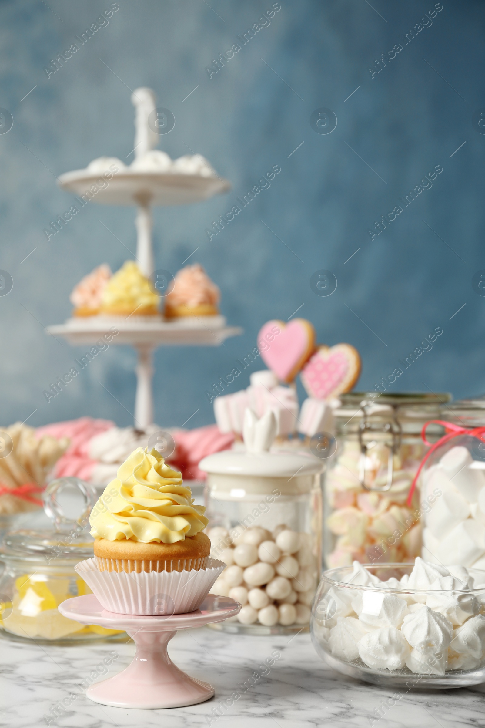 Photo of Candy bar with different sweets on white marble table against color background. Space for text