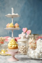 Photo of Candy bar with different sweets on white marble table against color background. Space for text