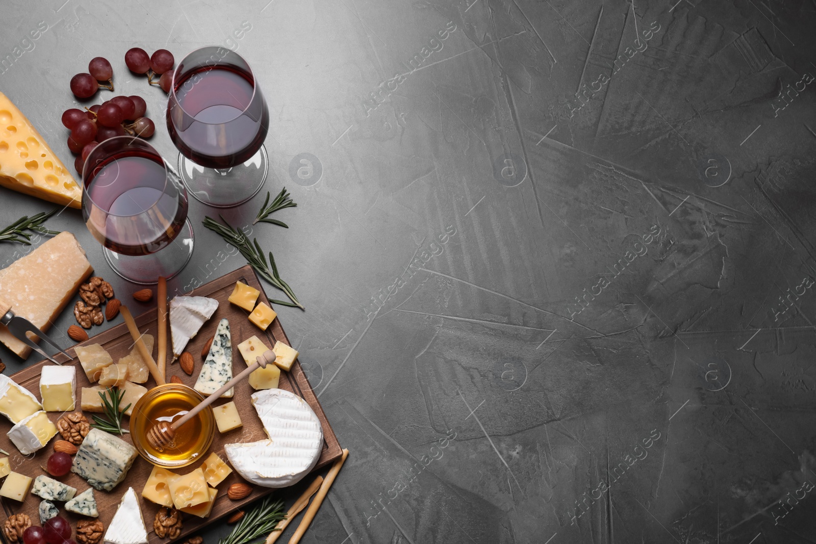 Photo of Cheese plate with honey, grapes and nuts on grey table, flat lay, Space for text