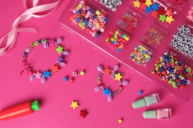 Photo of Handmade jewelry kit for kids. Colorful beads, ribbon and bracelets on bright pink background, flat lay