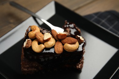 Piece of tasty homemade chocolate cake with nuts on plate, closeup