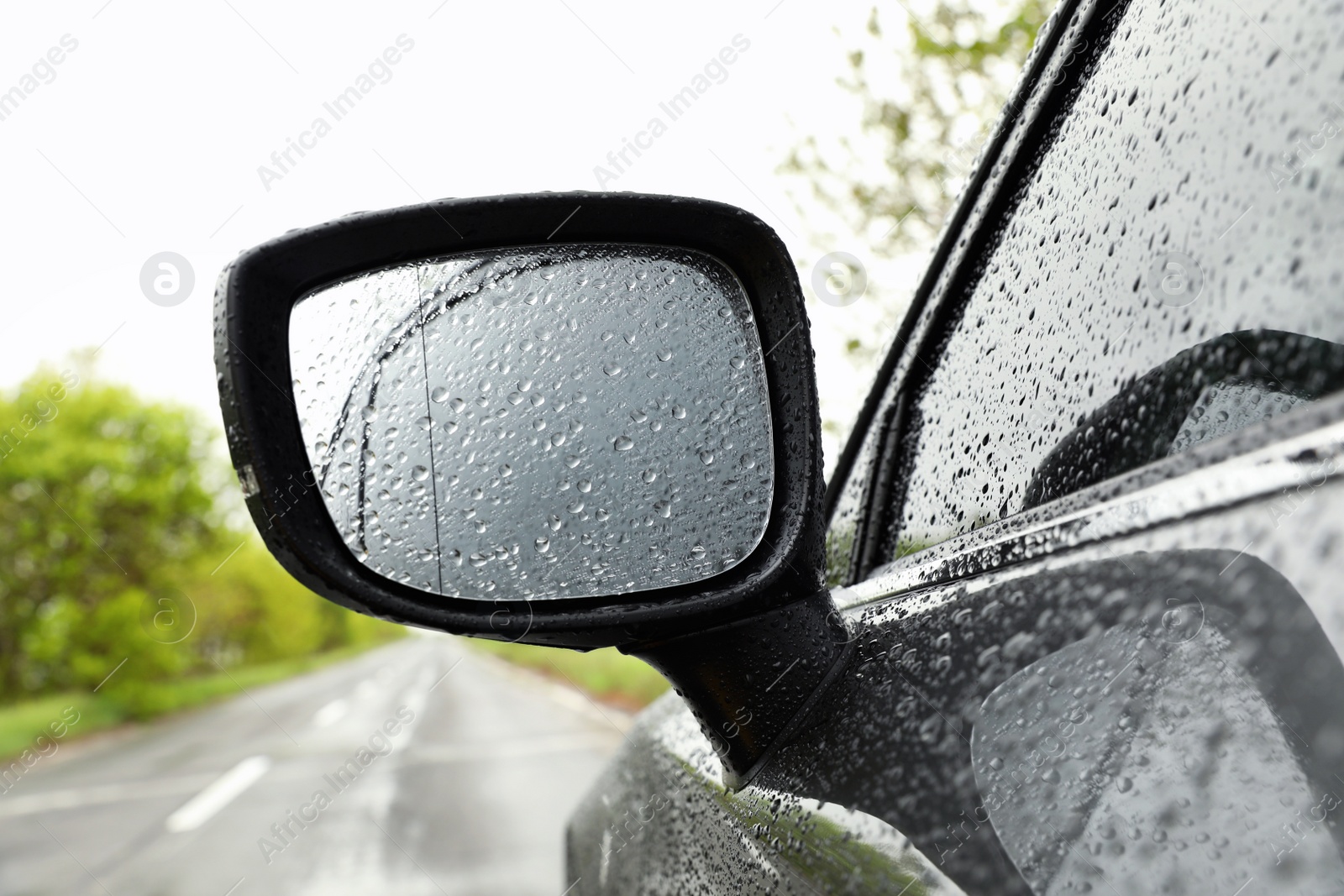 Photo of Closeup of car side rear view mirror with rain drops