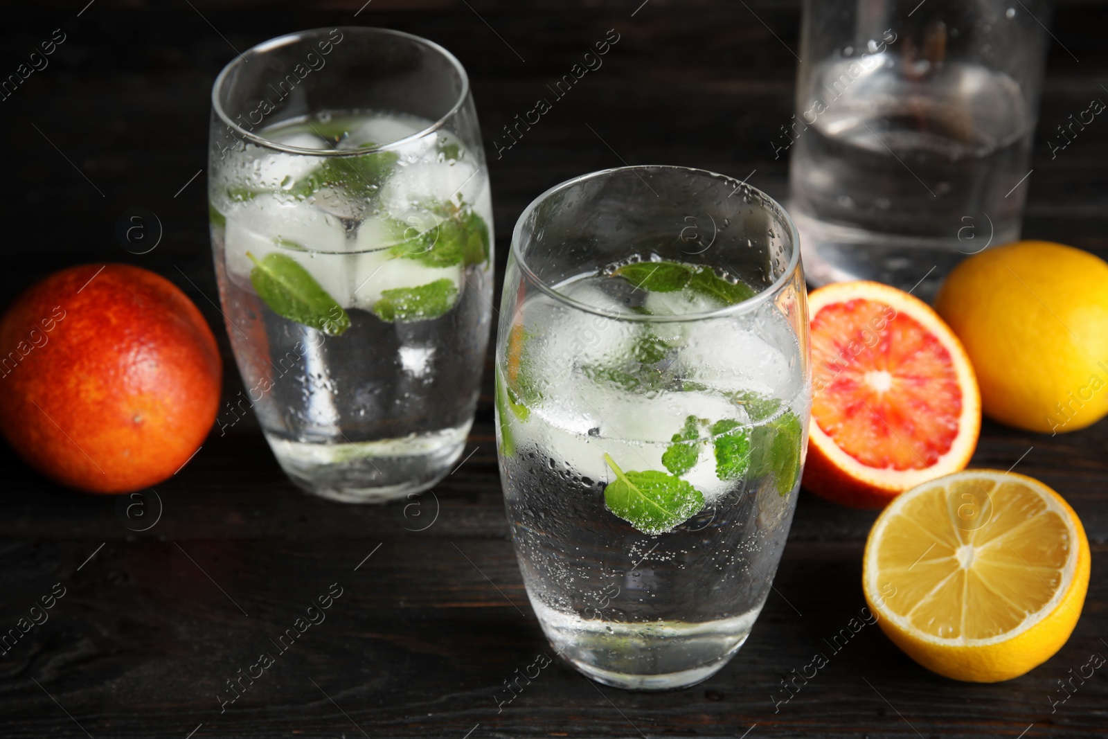 Photo of Composition with refreshing drink with mint and ice cubes in glasses on dark table