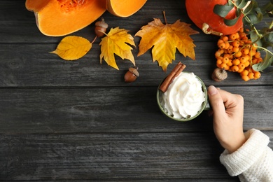 Photo of Woman holding cup with pumpkin spice latte on wooden background, top view. Space for text