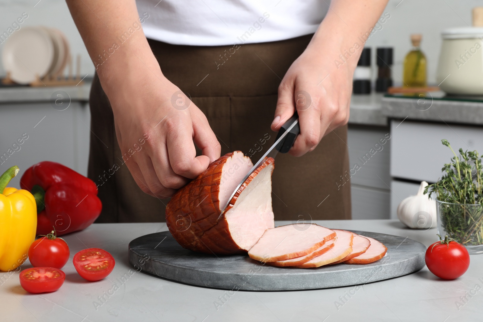 Photo of Man cutting delicious ham at grey table indoors, closeup