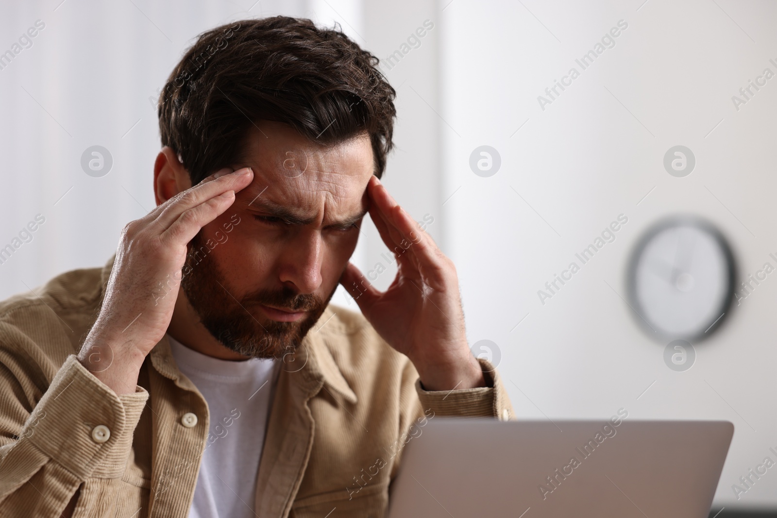 Photo of Tired man suffering from headache in office