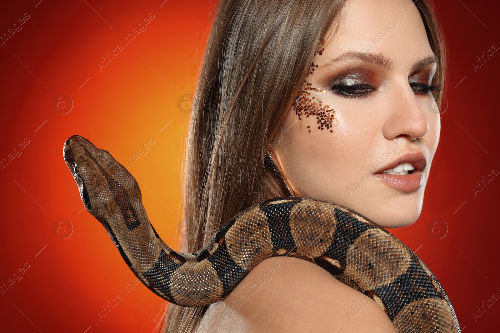 Photo of Beautiful woman with boa constrictor on bright colorful background, closeup