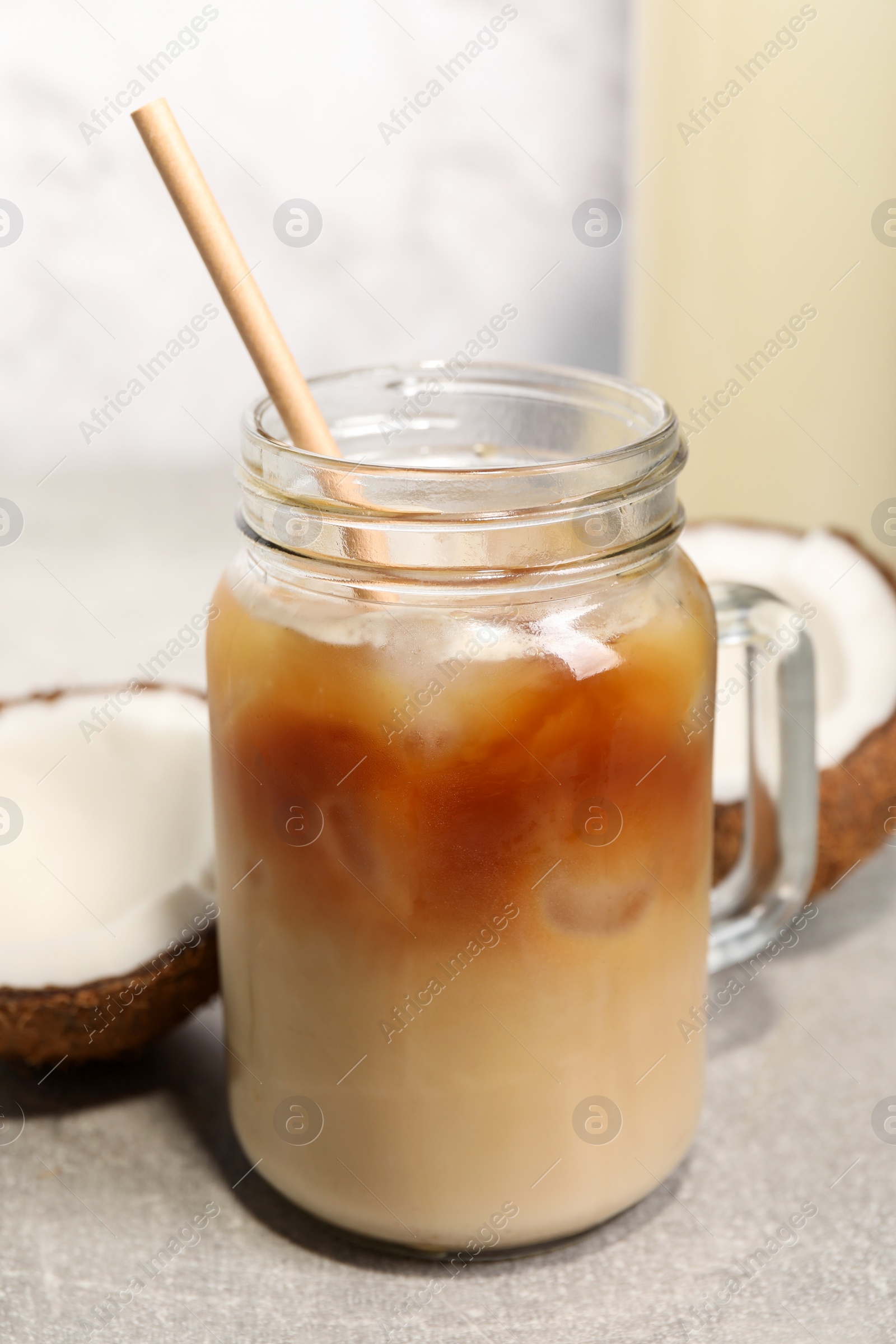 Photo of Mason jar of delicious iced coffee with coconut syrup on light grey table, closeup