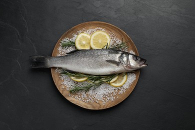 Sea bass fish and ingredients on black table, top view