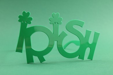 Photo of St. Patrick's day. Party glasses with word Irish on green background, closeup