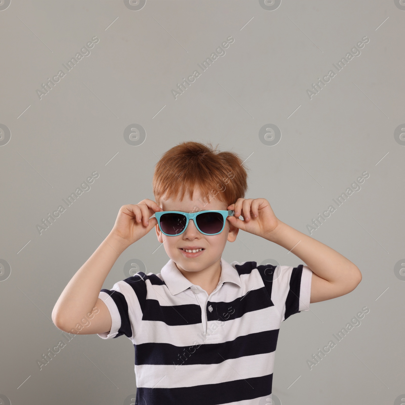 Photo of Cute little boy with sunglasses on light grey background