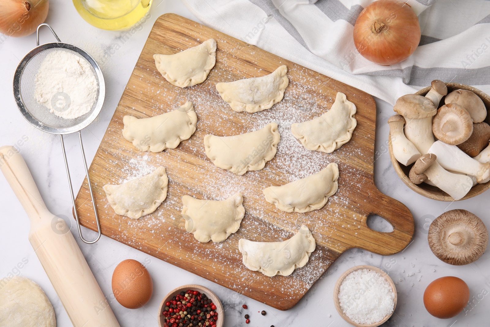 Photo of Process of making dumplings (varenyky) with mushrooms. Raw dough and ingredients on white marble table, flat lay