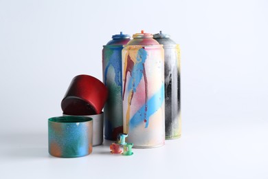 Many spray paint cans and caps on white background